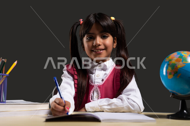 The role of schools in providing a safe and organized environment for learning, the pursuit of excellence and success,, a close-up portrait of a Saudi Arabian Gulf student wearing a school apron, holding a pen and looking at the camera, the importance of education in developing Saudi society, black background