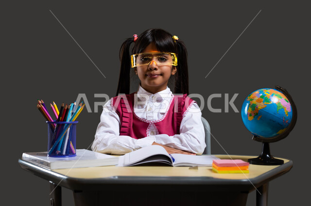 ايماءات الجدية والاهتمام بالعلم ، دور التعليم في بناء مستقبل مشرق للمجتمع السعودي، بورتريه مقرب لفتاة عربية سعودية خليجية ترتدي المريول المدرسي تضع النظارات الذكية ثلاثية الأبعاد وتجلس مكتفة اليدين، تطوير المناهج والمواد التعليمية في السعوديه، خلفية سوداء