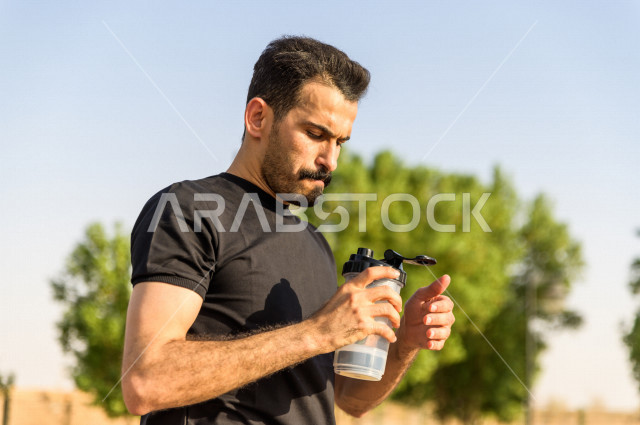 رجل شاب سعودي خليجي يمارس الرياضة الصباحية في الهواء الطلق ،ممارسة رياضة المشي ، ممارسة الرياضة على طريق الممشى المخصص للمشي ، نشاط بدني  للمحافظة على اللياقة و الصحة الجيدة ، ممارسة التمارين الرياضية 
