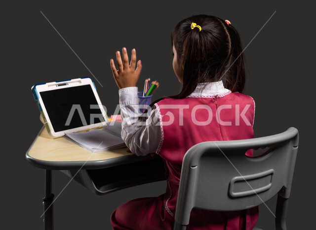 مفهوم التعلم عبر الانترنت، طرق ومناهج تعليمية حديثة ومتطورة في السعودية، متابعة الدروس عن طريق منصات التعلم عن بعد، بورتريه لطالبة عربية سعودية خليجية ترتدي اليونيفورم المدرسي وتجلس أمام طاولة الدراسة والتابلت، إيماءات التفاعل والمشاركة، خلفية سوداء.