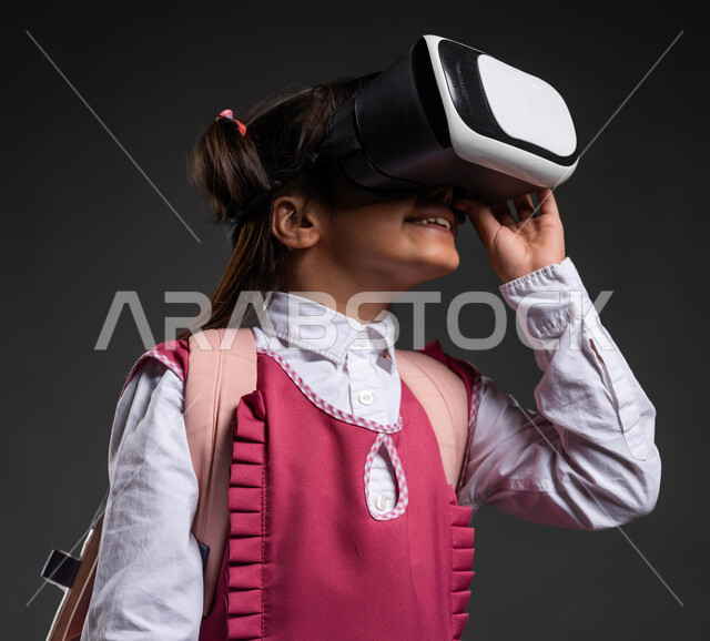The development of education methods using modern and advanced technologies and simulating the imaginary world, a close-up portrait of a smiling Saudi Gulf Arab girl wearing a school dress and school bag, wearing 3D virtual reality glasses, gestures of integration and focus, black background.