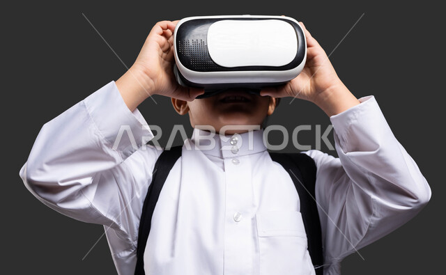 تطور أساليب التعليم باستخدام التقنيات الحديثة والمتطورة و محاكاة العالم الخيالي، بورتريه مقرب لفتى عربي خليجي سعودي يرتدي الثوب التقليدي ويحمل الحقيبة المدرسية يلبس نظارة الواقع الإفتراضي ثلاثية الأبعاد، ايماءات التفاعل والاندماج ، خلفية سوداء
