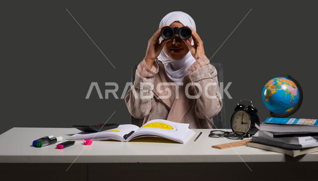 نشاطات لتحفيز العقل والفكر, رؤية مستقبلية لتحقيق النجاح والتفوق الدراسي , بورتريه لطالبة جامعية عربية خليجية سعودية محجبة ترتدي العباءة وتجلس على كرسي مريح تبتسم وتنظر إلى الكاميرا عبر المنظار ثنائي العينين ,  خلفية سوداء .