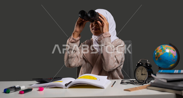 A future vision for achieving success and academic excellence, a portrait of a veiled Saudi Gulf Arab university student wearing an abaya and looking through binoculars, using binoculars to discover distant objects, black background