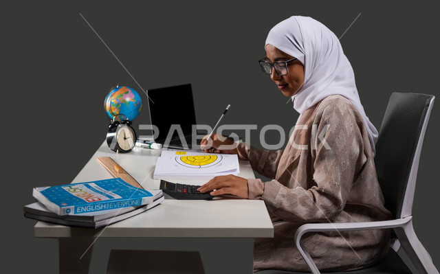 مفهوم التعليم المنزلي , بورتريه من الجانب لشابه عربية خليجية سعودية محجبة ترتدي العباءة والنظارة الطبية وتجلس على كرسي مريح , طالبة ثانوية تستخدم جهاز الحاسوب في تأدية واجباتها ,دور التكنولوجيا في تغيير أساليب التعليم التقليدية,   خلفية سوداء .