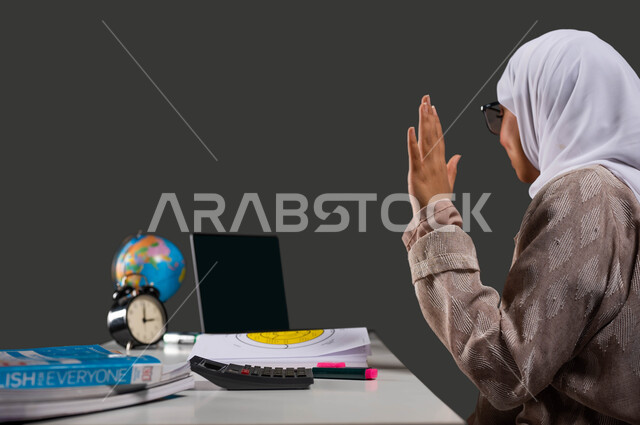 بث أونلاين للحصص المدرسية، بورتريه مقرب لطالبة ثانوي عربية سعودية خليجية محجبة ترتدي عباءة وتتفاعل مع الدرس عبر الانترنت، تطور العلم والتعليم في السعودية، تنمية مهارات الاتصال والتعاون من خلال التعليم الافتراضي، خلفية سوداء