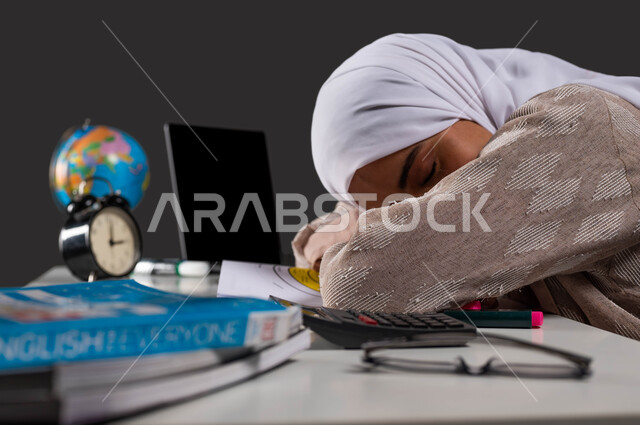 The importance of rest and good sleep in enhancing the mental and physical health of students, a close-up portrait from the side of a Saudi Arabian Gulf high school student wearing a colorful abaya, taking a nap while studying for lessons, studying late hours at night, fatigue and stress while studying, black background