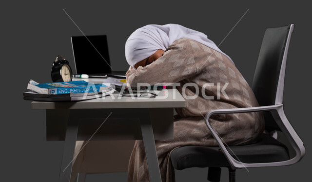 The importance of rest during the exam, the effect of good sleep on students’ achievement in school, a side portrait of a Saudi Arabian Gulf high school student wearing a colorful abaya taking a nap at the study table, fatigue and stress while studying, black background