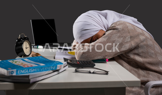 أثر النوم الجيد على تحصيل الطلاب في المدرسة، بورتريه مقرب من الجانب لطالبة ثانوي عربية سعودية خليجية ترتدي عباءة ملونة تأخذ قيلولة على طاولة الدراسة، أهمية الراحة اثناء المذاكره، خلفية سوداء