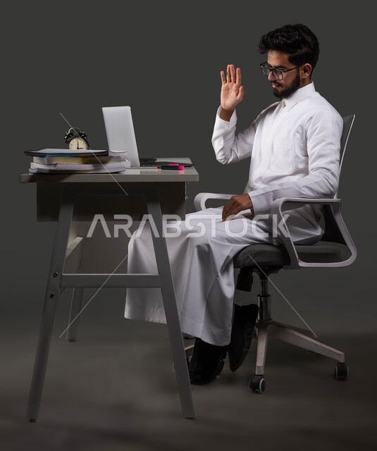 بث مباشر للحصص الدراسية، بورتريه لطالب ثانوي عربي خليجي سعودي يرتدي الزي التقليدي يتفاعل مع الحصة الدراسية عبر الانترنت، استخدام البرامج والتطبيقات الرقمية في التعلم، السعي للتفوق والنجاح، خلفية سوداء