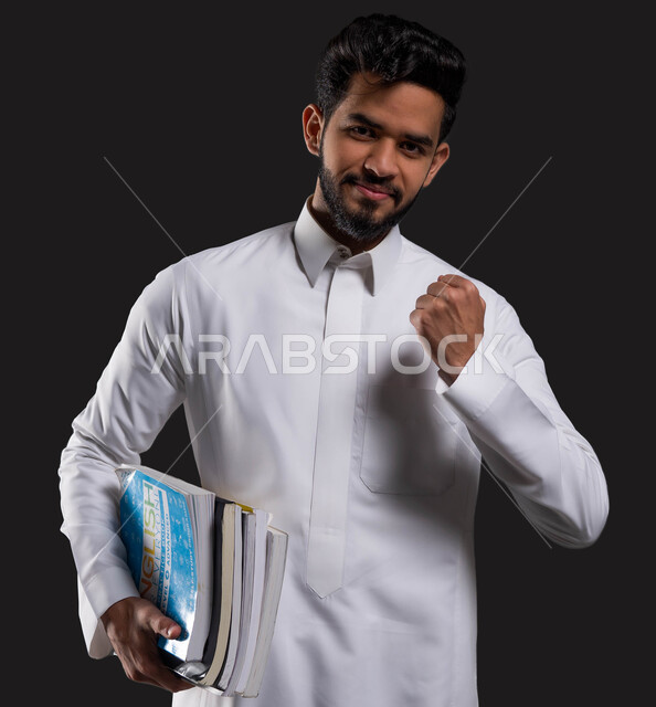 ايماءات القوة والشجاعه، اهمية التعليم في تطوير المجتمع السعودي، بورتريه مقرب لطالب جامعي عربي خليجي سعودي مبتسم يرتدي الزي التقليدي ويرفع قبضة يده للأعلى، العلم مفتاح التطور والنجاح، خلفية سوداء.