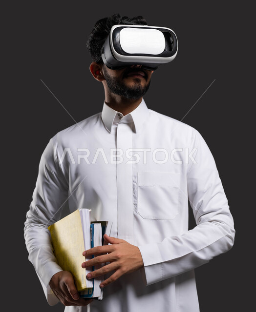 The role of virtual reality glasses in enhancing the absorption of information and students’ interaction with educational content, a close-up portrait of a Saudi Arabian Gulf high school student wearing traditional clothing, wearing virtual reality glasses and holding textbooks in his hand, black background.