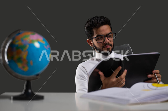 The importance of reading in expanding the horizons of knowledge and increasing information, the role of education in developing Saudi society, a close-up portrait of a Saudi Gulf Arab high school student wearing traditional clothing, wearing glasses and reading from his textbook, science is the key to development and success, black background.
