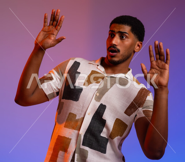 حماية النفس من ضرر خارجي, بورتريه مقرب لرجل عربي خليجي سعودي يرتدي الزي الكاجوال و يرفع يديه بإيماءات التوقف وعدم الاقتراب, القلق والاحتياط والابتعاد عن شيء ما, الشعور بالانزعاج وعدم الراحة،  خلفية ملونة