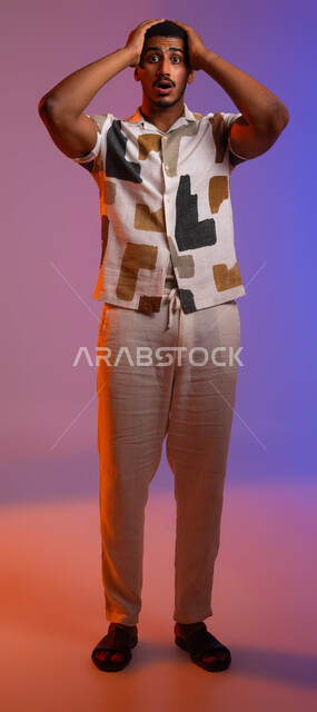 ايماءات وجه ويدين تدل على الصدمة، بورتريه مقرب لشاب عربي سعودي خليجي يرتدي ملابس كاجوال صيفية و يضع يده على رأسه ، تلقي اخبار سيئة غير متوقعة، خسارة مالية فادحة، خلفية ملونة