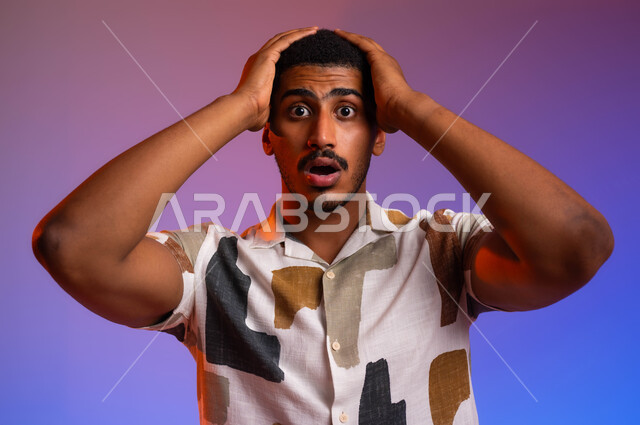 ايماءات وجه ويدين تدل على الصدمة، بورتريه مقرب لشاب عربي سعودي خليجي يرتدي ملابس كاجوال صيفية و يضع يده على رأسه ، تلقي اخبار سيئة غير متوقعة، خسارة مالية فادحة، خلفية ملونة
