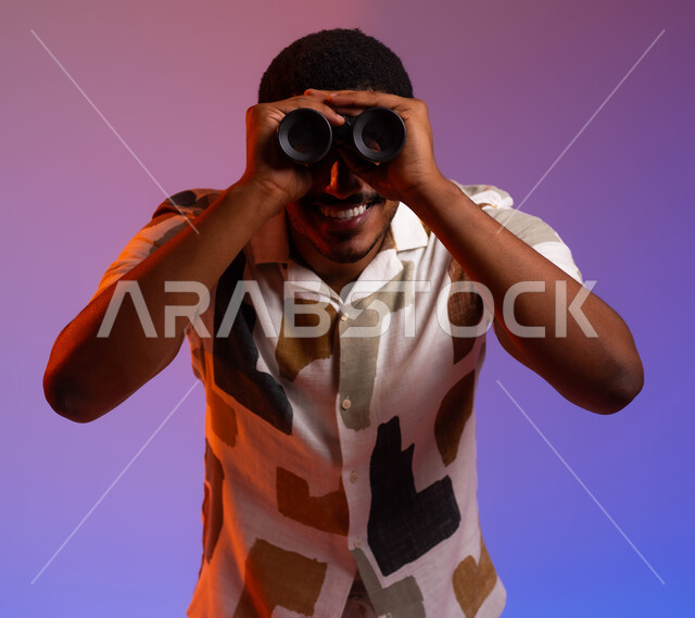 Seeing the world more clearly and accurately, a close-up portrait of a smiling Saudi Gulf Arab young man wearing a summer shirt and holding a dual-lens telescope over his eyes, future planning for goals and ambitions, the joy of exploration and adventure, a colorful background.