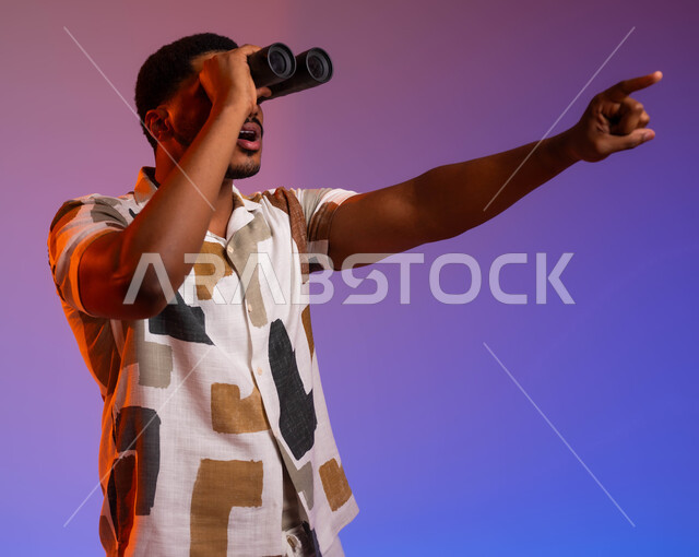 رؤية الفرص والتحديات المحتملة، بورتريه مقرب لشاب عربي سعودي خليجي مبتسم يرتدي الزي الكاجوال يضع المنظار على عينيه ويشير بإصبعه الى مكان ما، رؤية واضحة ومشرقة للمشاهد والتفاصيل، التخطيط المستقبلي للأهداف والطموحات، خلفية ملونة