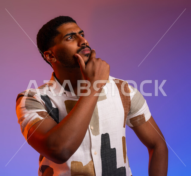 التخطيط للمستقبل والحياة، مفهوم التمعن والتركيز، حل المشكلات واتخاذ القرارات, ايماءات التأمل والتفكير والحيرة، بورتريه مقرب لرجل عربي سعودي خليجي يرتدي الزي الكاجوال يضع يده على ذقنه ويفكر في شيء ما، خلفية ملونة