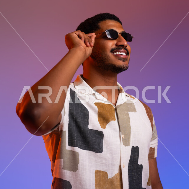 الإستعداد للرحلة السياحية، بورتريه مقرب لشاب عربي سعودي خليجي مبتسم يرتدي قميص صيفي ويضع النظارة الشمسية، ايماءات النشاط والحيوية للسفر، قضاء أوقات ممتعة خارج البلاد، الابتعاد عن ضغوط الحياة، خلفية ملونة