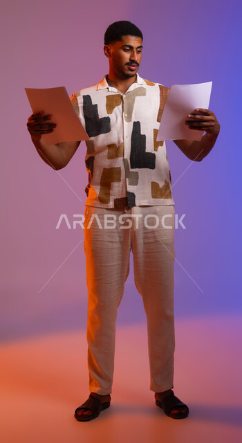التأكد من تطبيق الخطط والقواعد في المشروع، دراسة جدول الأعمال, بورتريه لرجل عربي خليجي سعودي يرتدي الزي الكاجوال يحمل بيده مجموعة من الاوراق الفارغة، مراجعة سجلات وملاحظات العمل، صورة الجسم بالطول الكامل, خلفية ملونة .
