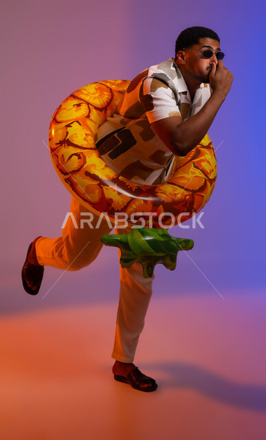Water sports activities, portrait of a young Saudi Arabian Gulf man wearing casual clothes, sunglasses and a buoy, gestures of preparing for diving and swimming, enjoying summer trips on the sea, full-length body portrait, colored background