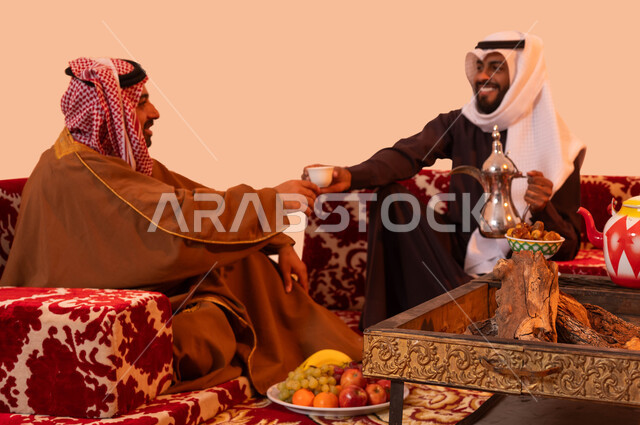 عادات عريقة في تقديم القهوة الساخنة، حورارات ونقاشات بين الأصدقاء، شاب يقوم بصب القهوة للضيوف، بورتريه مقرب لرجلان عربيان خليجيان سعوديان يرتديان الزي التقليدي يستمتعان برحلة تخييم برية، إيماءات الفرح والبشاشة وحسن الاستقبال، خلفية بيج.