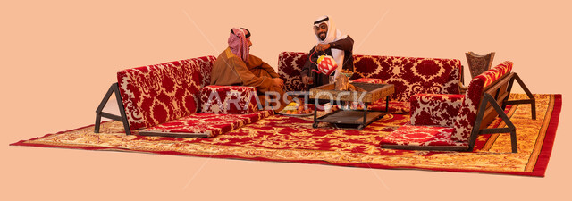 الاستمتاع بأجواء التخييم الهادئة, حورارات ونقاشات بين الأصدقاء، كشتة برية شبابية، بورتريه لرجلان عربيان خليجيان سعوديان يرتديان الزي التقليدي يتبادلان الحديث يتسامران، شاب يقوم بصب الشاي للضيوف، إيماءات البشاشة وحسن الاستقبال، خلفية بيج.