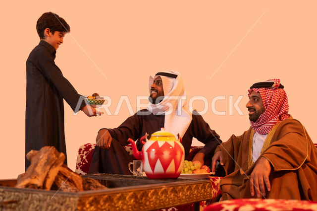 جلسات ترفيهية في الهواء الطلق، عادات وتقاليد سعودية اصيلة في حسن الاستقبال والكرم، بورتريه لولد عربي خليجي سعودي يقوم بتقديم الضيافة،  تبادل القصص والحكايات التراثية أثناء الكشتة البدوية، مشاركة الأفكار والخبرات وتبادل المعرفة بين الشباب، خلفية بيج