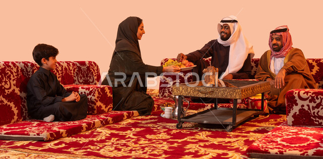 قضاء أوقات عائلية ممتعة، حسن الضيافه والاستقبال، مخيمات سياحية ترفيهية، تقديم الفاكهة للضيوف، إيماءات البشاشة والترحيب، بورتريه لعائلة عربية خليجية في نزهة خارجية، الاستمتاع في الاجواء الشتوية الهادئة، خلفية بيج.