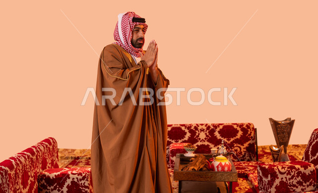 كشتة بر شبابية شعبية، الأجواء الهادئة في أماكن التخييم، الشعور بالبرد والصقيع, أسلوب الحياة البدوية القديمة, مخيمات وأجواء شتوية، بورتريه مقرب لرجل عربي خليجي سعودي يرتدي البشت والشماغ التقليدي يقف أمام الموقد، خلفية بيج.