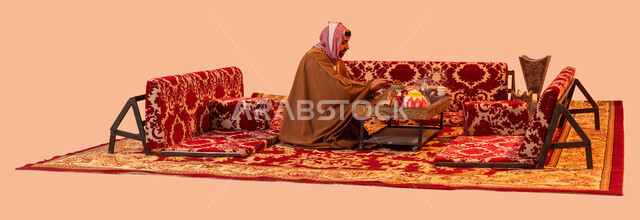 جلسة بر شبابية شعبية، أسلوب الحياة القديمة، إيماءات التدفئة على الموقد, مخيمات وأجواء شتوية، بورتريه لرجل عربي خليجي سعودي يرتدي البشت والشماغ التقليدي يجلس أمام شعلة من النار ، الأجواء الهادئة في أماكن التخييم، خلفية بيج.