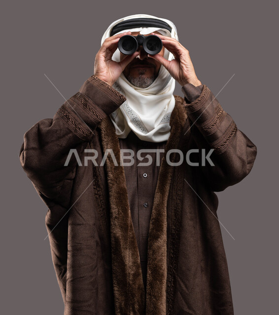 A vision of the future and a love of adventure and discovery, a close-up portrait of an elderly Saudi Arabian Gulf man wearing a winter dress and wearing the traditional headband and ghutra trying to see distant things through a telescope, camping in the winter, a gray Khalifa.