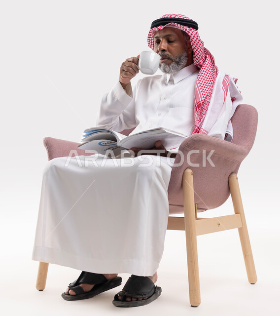 التزود بالعلم والمعرفة، قضاء وقت الفراغ بالتثقيف والتعلم، مفهوم محو الأمية، بورتريه لرجل كبير بالسن عربي سعودي خليجي يرتدي الشماغ والثوب التقليدي يشرب القهوة ويمارس هواية قراءة الكتب المفيدة في وقت الفراغ، خلفية بيضاء