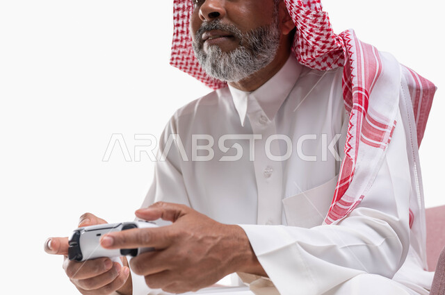 Spending a fun and entertaining time playing, interacting and merging with PlayStation games, modern electronic entertainment technologies, a close-up portrait of an elderly Saudi Arabian Gulf man wearing a shemagh and traditional thobe, sitting on a comfortable chair holding a joystick in his hand, playing video games, white background.