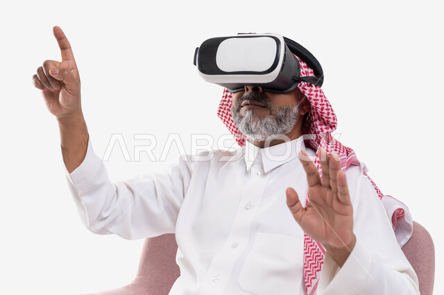 استخدام حاسة اللمس ومحاولة نقر شيء ما, مشاهدة الأفلام عبر نظارة الواقع الافتراضي في آر, التفاعل والاندماج ومحاكاة العالم الخيالي, بورتريه مقرب لرجل كبير بالسن عربي خليجي سعودي يرتدي الثوب التقليدي والنظارة ثلاثية الابعاد يرفع يديه للأعلى, خلفية بيضاء