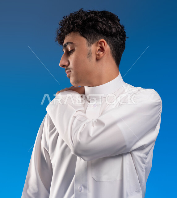 شد عضلي في الرقبه ،التهاب العضلات والمفاصل، الإحساس بالتعب والإرهاق, بورتريه مقرب لشاب عربي سعودي خليجي يضع يده على رقبته بإيماءات الألم في الأكتاف، الحاجه للعلاج و وضع خطة علاجية, طلب المساعده للذهاب الى المستشفى، خلفية زرقاء.