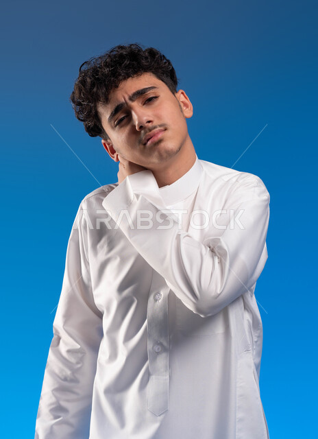 التهاب العضلات والمفاصل، الإحساس بالتعب والمرض والإرهاق, بورتريه مقرب لشاب عربي سعودي خليجي يضع يده على رقبته و ينظر الى الكاميرا ،إيماءات الألم في الأكتاف، الحاجه للعلاج و وضع خطة علاجية, طلب المساعده للذهاب الى المستشفى، خلفية زرقاء.
