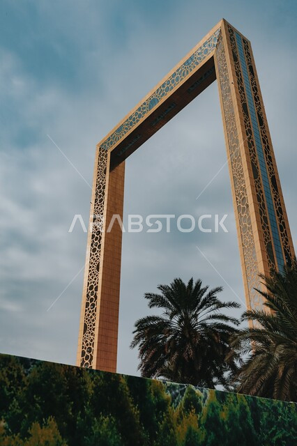 The architectural engineering art of the Dubai city frame, urban growth and development in the Emirates, a glass building in golden colors, green palm trees in broad daylight, famous landmarks and tourist places in Dubai