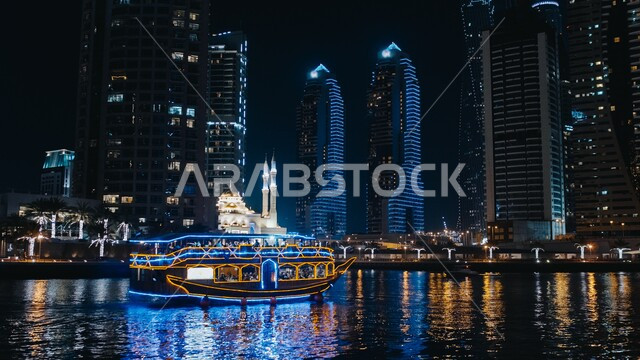 الفن الهندسي المعماري للأبراج وناطحات السحاب في الإمارات العربية المتحدة، صورة ليلية لمركب نقل السياح في بحر مارينا دبي، إستخدام وسائل النقل والمواصلات البحرية، النمو والتطور العمراني في دبي، السياحة في الإمارات