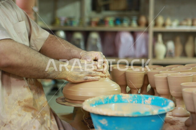 اواني خرفية مصنوعة من الطين، صورة مقربة لأيدي رجل يقوم بصناعة الفخار، حرف وصناعات يدوية شعبية سعودية، صنع الاواني والجرار الفخارية، تراثيات وشعبيات