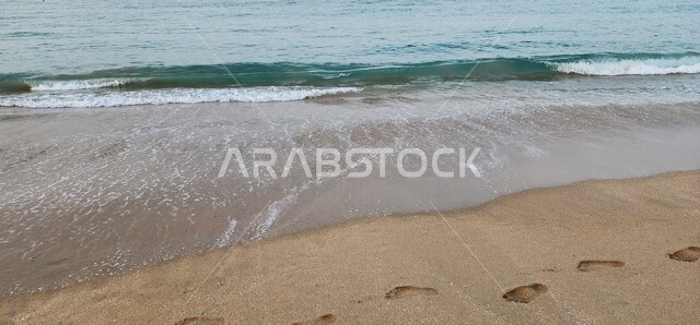  منظر أمواج البحر على الرمال الذهبية الناعمة في وضح النهار، التكوين الطبيعي البحري على شاطئ سلطنة عمان، رحلات ترفيهيه ساحليه، أماكن و معالم طبيعية سياحية مشهورة.