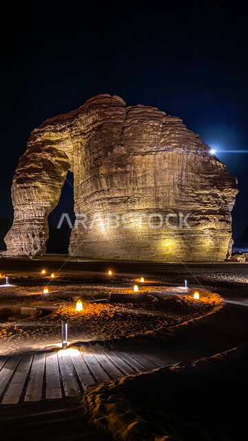 The view of the moon and lighting at night in the desert, Elephant Rock in Al-Ula Governorate in the Kingdom of Saudi Arabia at night, ancient historical monuments, mountain peaks and heights, rock formations in desert areas, tourist places in Saudi Arabia.