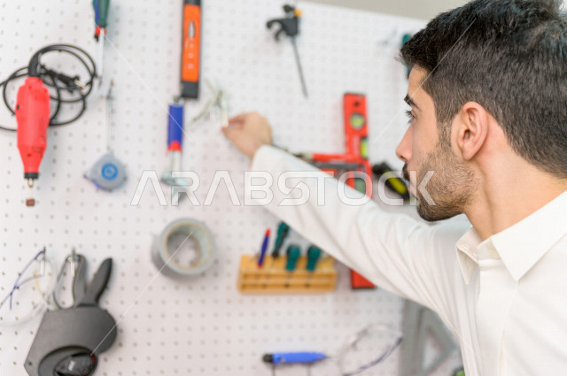 شاب سعودي مبتكر يقوم بفحص الادوات و المعدات في المختبر ،استخدام الذكاء الاصطناعي للتصنيع ، اكاديمية مختصة بالعلوم والتكنولوجيا والهندسة والرياضيات