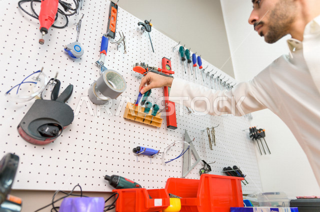 شاب سعودي مبتكر يقوم بفحص الادوات و المعدات في المختبر ،استخدام الذكاء الاصطناعي للتصنيع ، اكاديمية مختصة بالعلوم والتكنولوجيا والهندسة والرياضيات