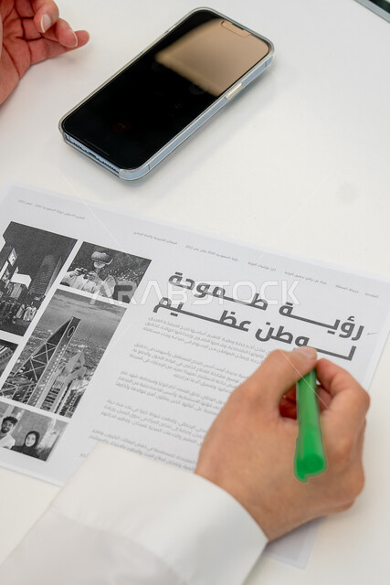 استخدام التقنيات الحديثة في بناء واقع أفضل بسواعد أبناء الوطن، صورة مقربة ليد رجل عربي خليجي سعودي يحمل بيده قلم ويشير إلى عبارة رؤية طموحة لوطن عظيم، رؤية مستقبلية سعودية 2030 ، الاهتمام بالتطور والنمو وتحقيق اهداف السعودية 