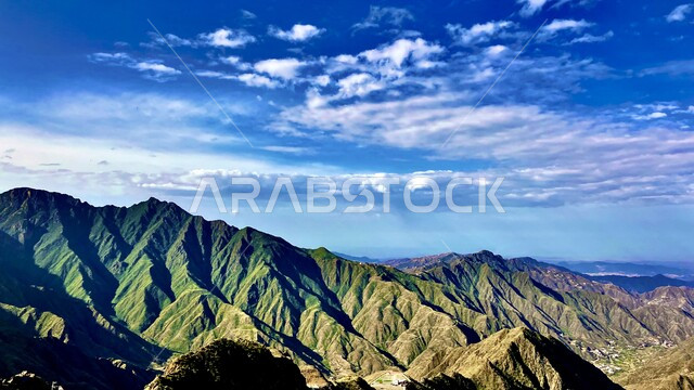 سلسلة جبال تنومة في منطقة عسير جنوب غرب المملكة العربية السعودية، الأشجار والنباتات الخضراء على القمم والمرتفعات الجبلية، السماء المليئة بالغيوم والسحب الكثيفة، أماكن ومعالم طبيعية سياحية.