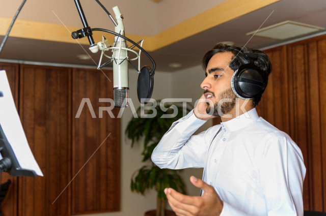 مذيع سعودي داخل الاستديو ، تسجيل الصوت من خلال المايكروفون ،  استديو تسجيل صوتي ، بث مباشر ، فريق الاعداد ، الاذاعة الصوتية ، نشرات اخبارية