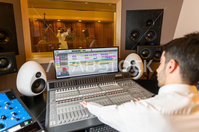 شاب سعودي يعمل كمرسال خارج الاستديو ،يعالج الاصوات المسجلة داخل الاستديو عن طريق برمجيات صوتية من خلال جهاز الحاسوب المخصص ، استديو تسجيل صوتي ، بث مباشر ، فريق الاعداد ، الاذاعة الصوتية ، نشرات اخبارية