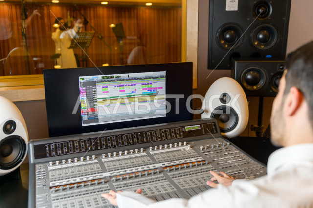 شاب سعودي يعمل كمرسال خارج الاستديو ،يعالج الاصوات المسجلة داخل الاستديو عن طريق برمجيات صوتية من خلال جهاز الحاسوب المخصص ، استديو تسجيل صوتي ، بث مباشر ، فريق الاعداد ، الاذاعة الصوتية ، نشرات اخبارية